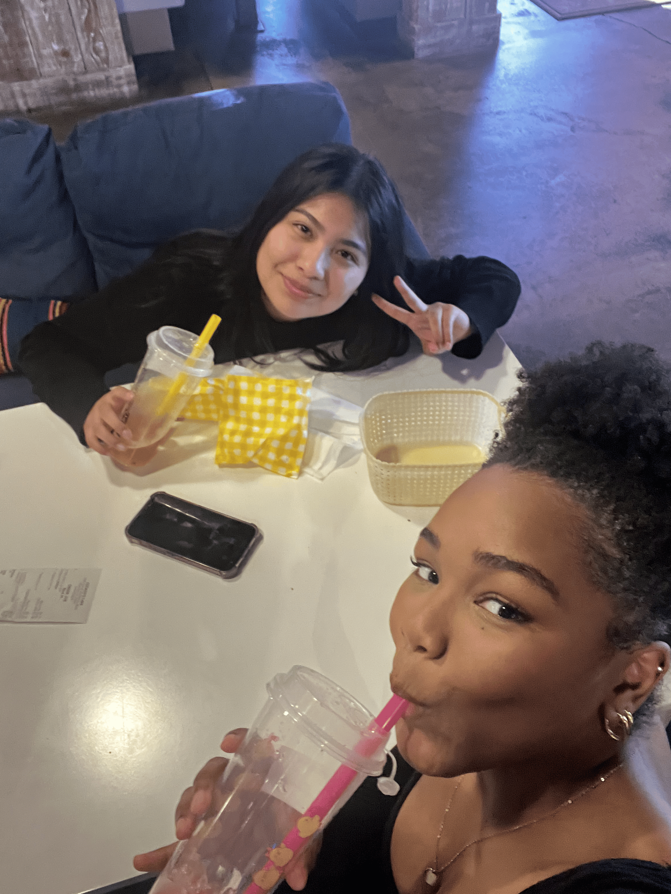 Drinking boba with a friend making a peace sign
